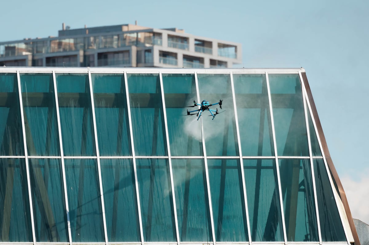 Autonomous drone performing aerial washing near glass facade