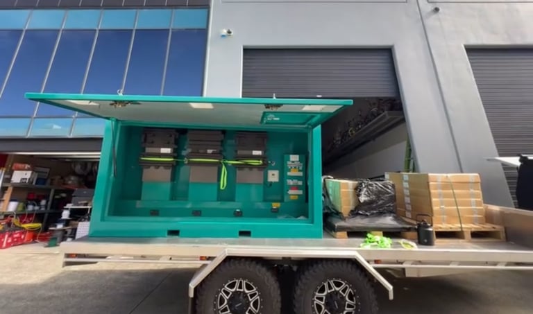 Turquoise food truck trailer with service window parked outside industrial building with solar panels